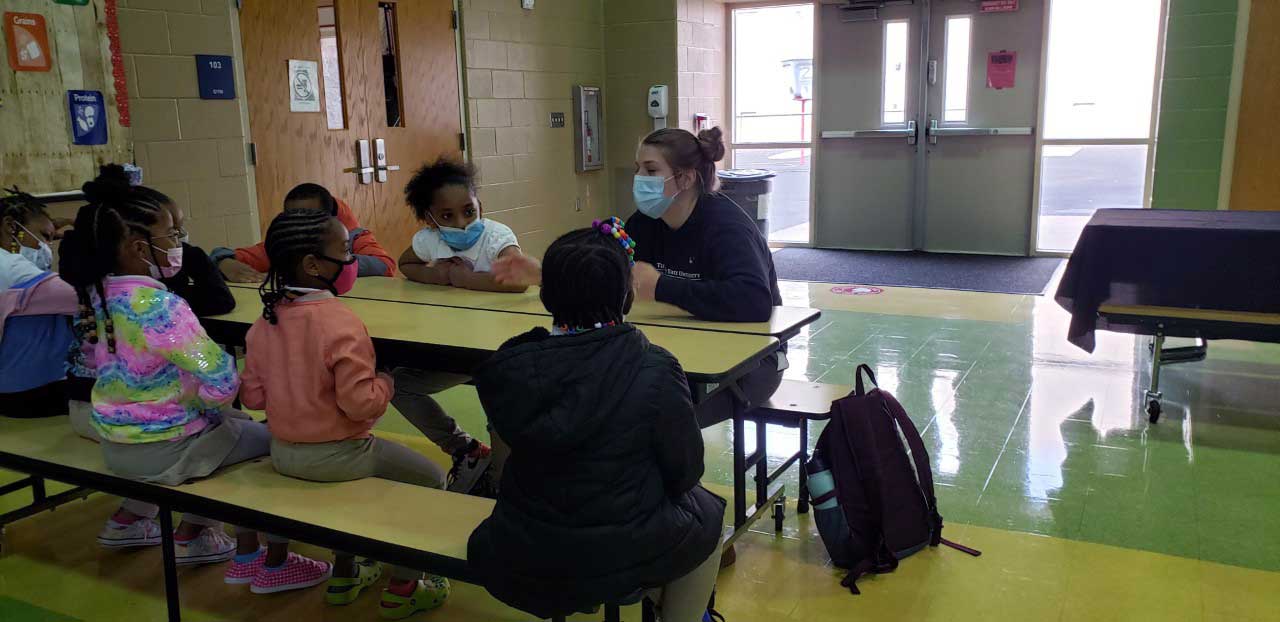 children and adult sitting at a table listening