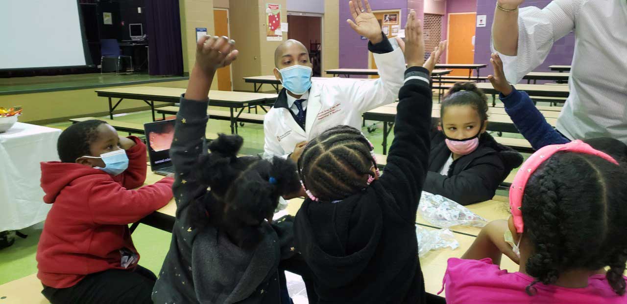 adult and children raising their hand sitting at a table