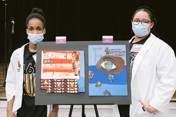 photo of two students posing in front of their artwork