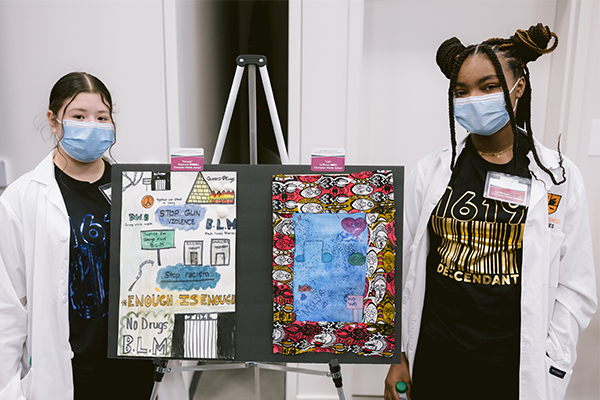 photo of two students posing in front of their artwork