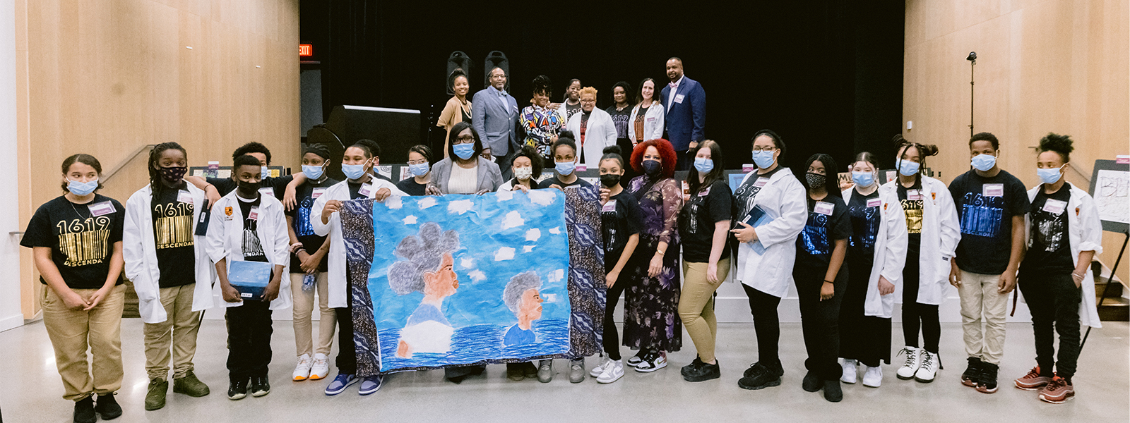 photo of group of all the students, faculty and staff, and Nikole Hanna-Jones holding artwork