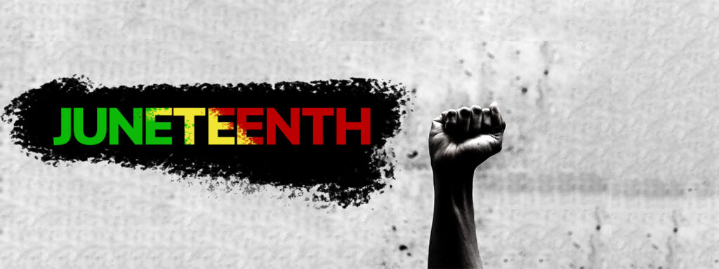 An hand in a fist raises triumphantly with the word "Juneteenth" next to it in green, yellow and red.