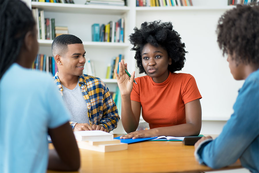 Black student raising their hand next to a group of people