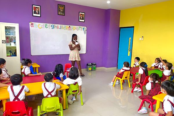 A student standing in front of a group of younger Indonesian students.