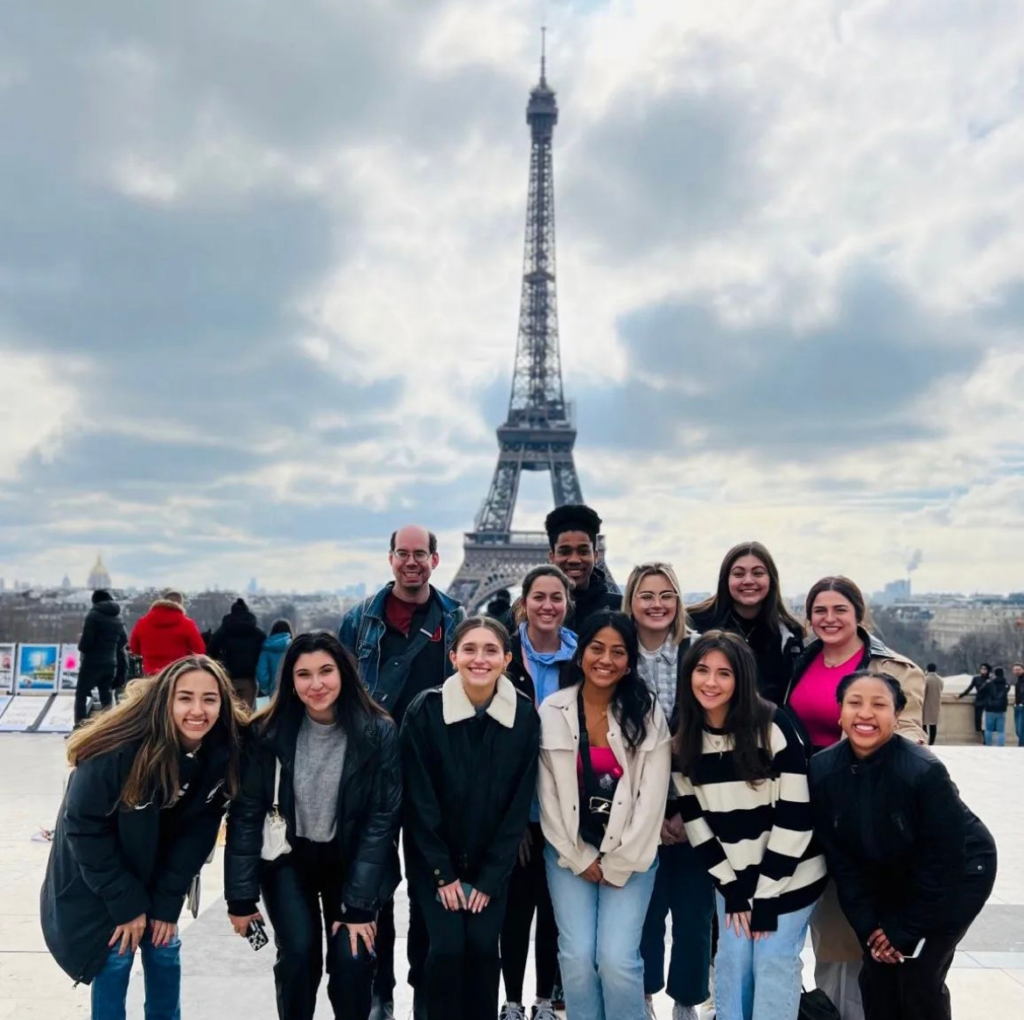 A group of people smile standing in front of the Eiffel Tower