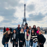 A group of people smile standing in front of the Eiffel Tower