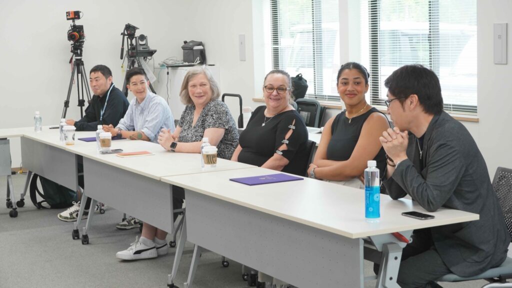 Students and faculty having a discussion in a classroom while sitting at desks